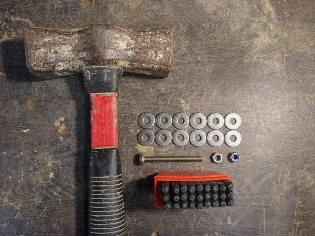 A set of stainless steel bolts, nuts and washers, a hammer and stamps